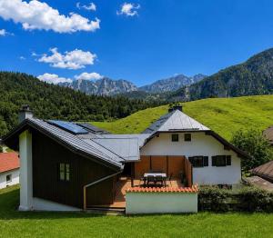 a house with a picnic table in front of a mountain at NaturZeit Melleck in Schneizlreuth