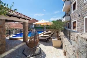a patio with a hammock and an umbrella next to a pool at Apartman Kunjić in Krimovice