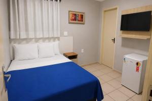 a bedroom with a blue and white bed and a television at Pousada Estrela Dourada in João Pessoa