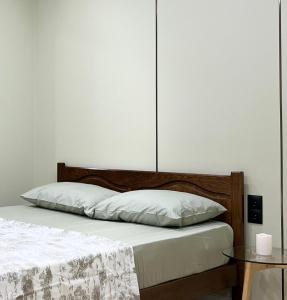 a bed with white sheets and a wooden headboard at Modern Olive Home in Căuşeni