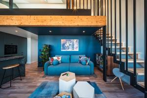 a living room with a blue couch and stairs at appartement Picasso - une évasion face à l'océan in Santec