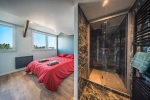 a bedroom with a shower and a bed with a red blanket at appartement Picasso - une évasion face à l'océan in Santec