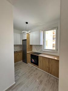 a kitchen with wooden cabinets and a window in it at A&H Apartment 2 in Shëngjin +16 photos