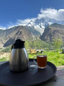 a cup of tea and a tea pot on a table with mountains at KOH E QAF HUNZA in Hini