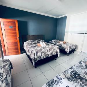 two beds in a room with blue walls at Pousada Dipajuçara in Maceió