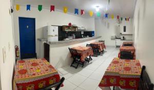 a room with tables and chairs and a kitchen with flags at Pousada Dipajuçara in Maceió