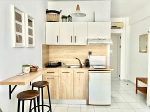 a kitchen with white cabinets and a sink and stools at Thalassa Garden Studios in Pefkochori