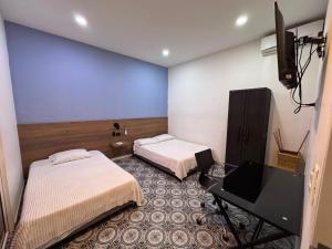 ein Zimmer mit zwei Betten und einem Fernseher in der Unterkunft Hotel San Telmo in Buga