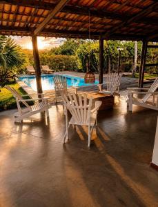 a patio with white chairs and a table and a pool at Pousada Villa Jodie in Fortim