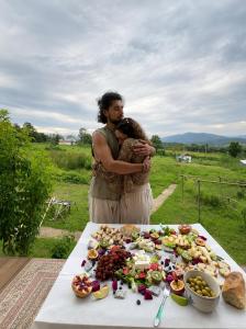 a man holding a child in front of a table of food at Garden de Arts in Pai