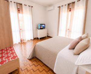 a bedroom with a white bed and a television at Casa Lupoli in Caserta