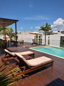 a deck with lounge chairs and a swimming pool at Ah Xok suites 5a Avenida in Playa del Carmen