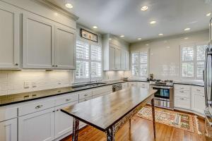 a kitchen with white cabinets and a wooden table at Luna Sea in Edisto Beach +38 photos