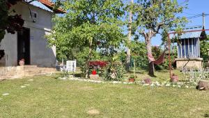 a garden with a hammock and some trees and a house at Dragačevska kuća na bregu- Heritage House in Viča