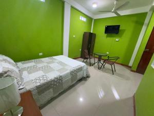a bedroom with green walls and a bed and a table at JAARR Alojamientos in Pucallpa