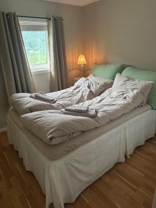 an unmade bed in a bedroom with a window at Koselig hus i Beisfjord in Narvik