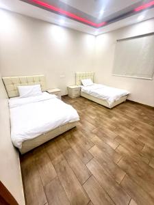 two beds in a room with wooden floors at شاليهات زارا 3 in Taif