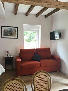 a living room with a red couch and two chairs at Domaine le bas bois in Neuville-sur-Sarthe