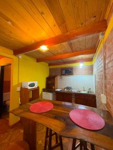 a kitchen with a wooden table with two red plates on it at Cabaña en la Naturaleza, próximo a las Cataratas - Oré Lodge in Puerto Iguazú