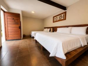 a bedroom with two beds and a wooden door at Villa Maria Hotel in Valle de Bravo