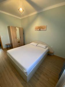 a large white bed in a room with a wooden floor at Christina Apartment in Drama