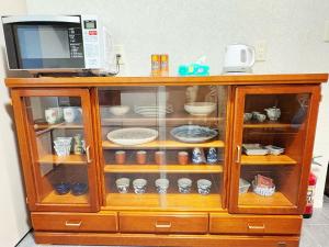 a cabinet with a microwave and dishes in it at Hitori Otaru in Otaru +2 photos