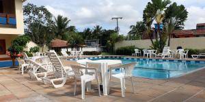 un grupo de mesas y sillas blancas junto a una piscina en Coroa Bella Praia Hotel, en Coroa Vermelha