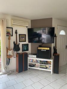a living room with a tv and guitars on the wall at Villa Cazaux in La Teste-de-Buch