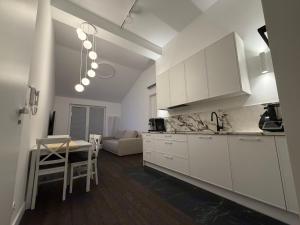 a kitchen with white cabinets and a living room at Apartament Brzeg in Augustów
