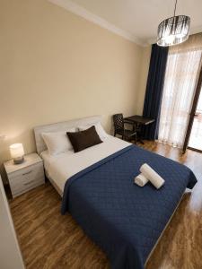 a bedroom with a large bed with a blue blanket at Sunny Hotel in Kobuleti