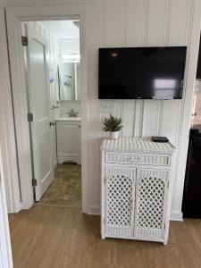 a bathroom with a television on a wall with a white cabinet at 2 Minute Walk to Beach, Cape Cod Escape in Dennis Port