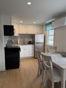 a kitchen with a table and a black refrigerator at 2 Minute Walk to Beach, Cape Cod Escape in Dennis Port
