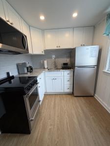 a kitchen with white cabinets and a stainless steel refrigerator at 2 Minute Walk to Beach, Cape Cod Escape in Dennis Port