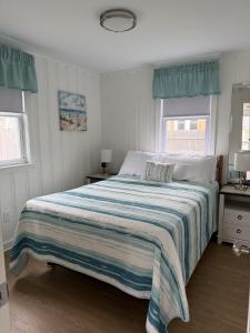 a bedroom with a large bed with a striped blanket at 2 Minute Walk to Beach, Cape Cod Escape in Dennis Port +12 photos