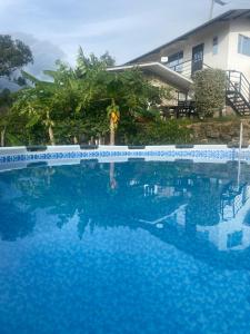 a swimming pool with blue water in front of a house at La bendición de sunnyvale cabaña pequeña 4 personas in La Vega