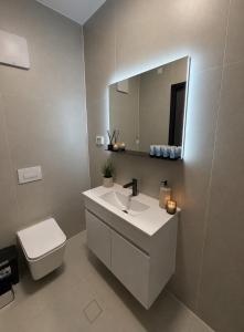 a bathroom with a sink and a toilet and a mirror at סוויטות אקווה איירפורט בוטיק & גרדן - By SEAELO in Eilat +14 photos
