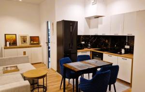 a kitchen with a table and blue chairs in a room at BOOGIE Home Nawrot 13 in Łódź