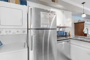 a stainless steel refrigerator in a kitchen with white cabinets at Driftwood Villa - 262 in Edisto Beach +11 photos