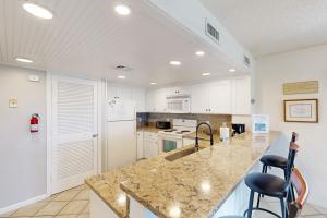 a kitchen with a marble counter top and white cabinets at Bay Creek Villa - 202 in Edisto Beach