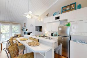 a kitchen with a table and a refrigerator at Driftwood Villa - 267 in Edisto Island +9 photos