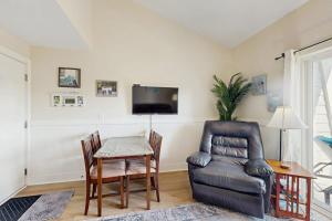 a living room with a table and a chair and a television at Driftwood Villa - 287 in Edisto Beach