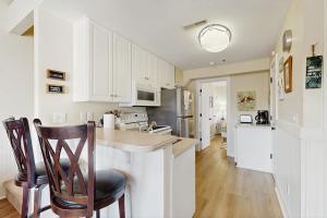 a kitchen with white cabinets and a counter and chairs at Driftwood Villa - 287 in Edisto Beach