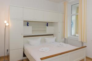 a white bedroom with a bed with white shelves at Villa Meeresgruss in Ostseebad Sellin