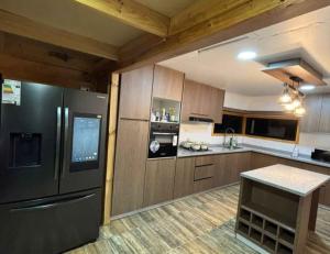 a kitchen with a stainless steel refrigerator and wooden cabinets at Hospedaje marylin in La Serena