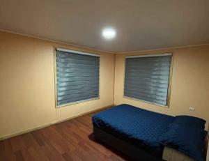a bedroom with a bed and two windows with blinds at Hospedaje marylin in La Serena