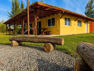a yellow house with a wooden bench in front of it at Quinta La llama violeta in Campana