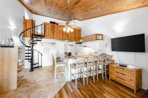 a kitchen with a bar with chairs and a tv at Driftwood Villa - 259 in Edisto Beach