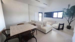 a living room with a couch and a table and chairs at סוויטות אקווה איירפורט בוטיק & גרדן - By SEAELO in Eilat