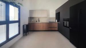 a kitchen with black and white appliances and windows at סוויטות אקווה איירפורט בוטיק & גרדן - By SEAELO in Eilat