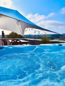 a large swimming pool with a blue and white umbrella at Mediterrane Ferienwohnung mit Whirlpool und Weitblick in Merchweiler +19 photos